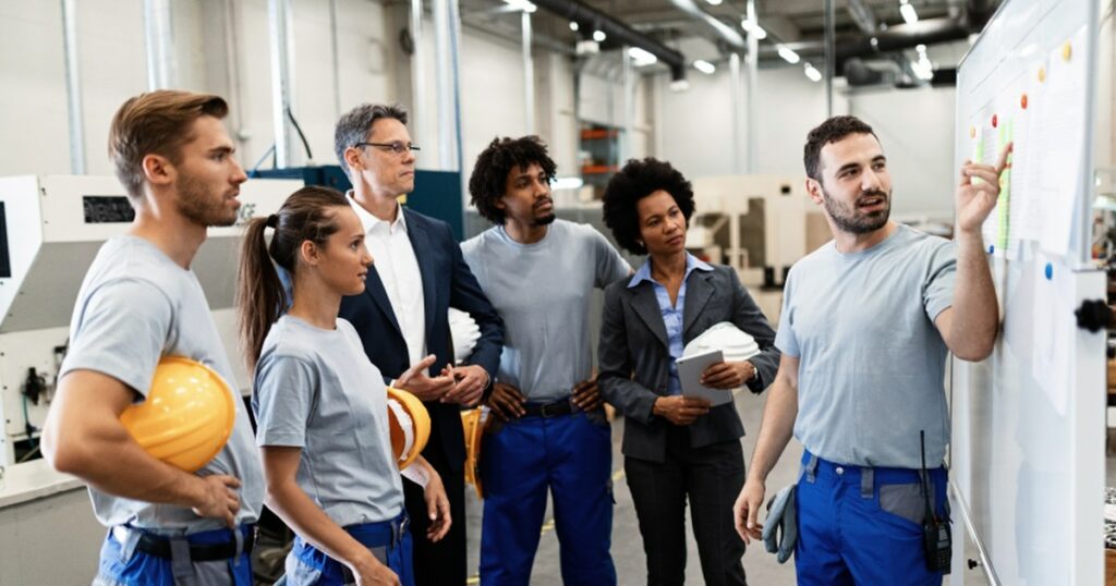 Equipo de operarios y responsables de distintas áreas revisando la planificación de la prevención en una planta industrial