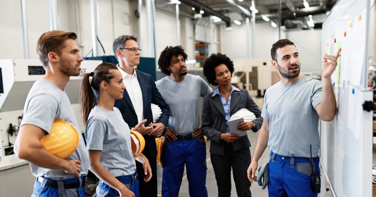 Equipo de operarios y responsables de distintas áreas revisando la planificación de la prevención en una planta industrial